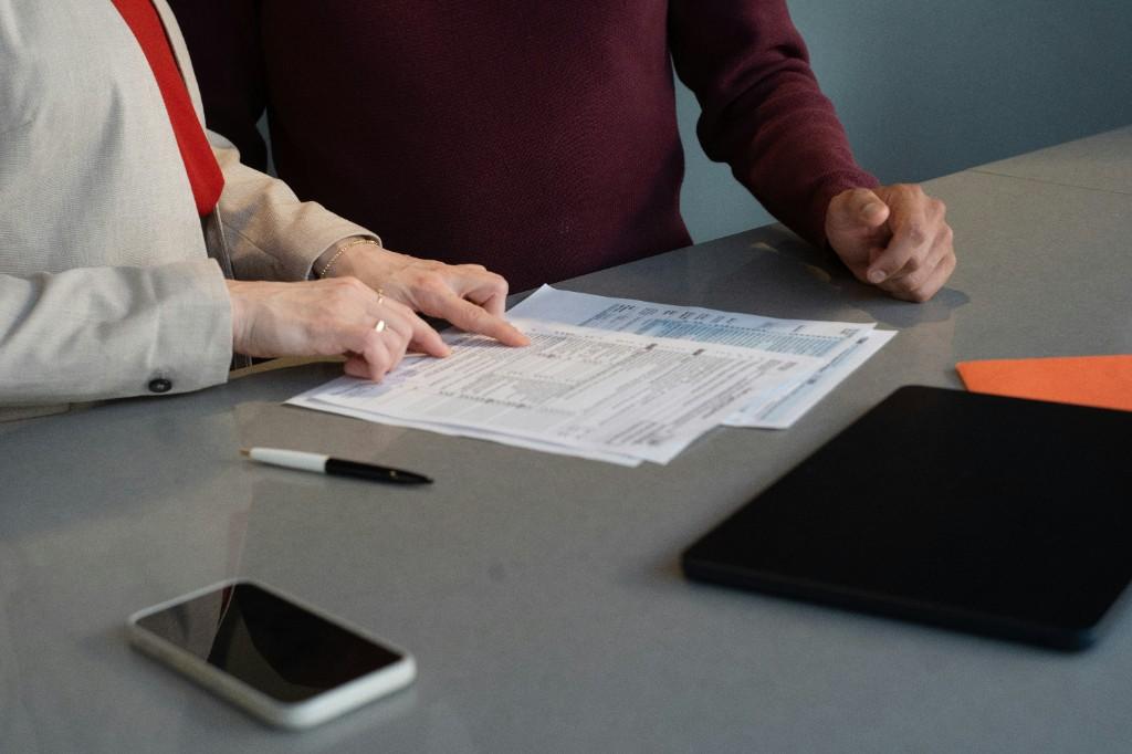 Two professionals reviewing printed documents at a desk during a consultation